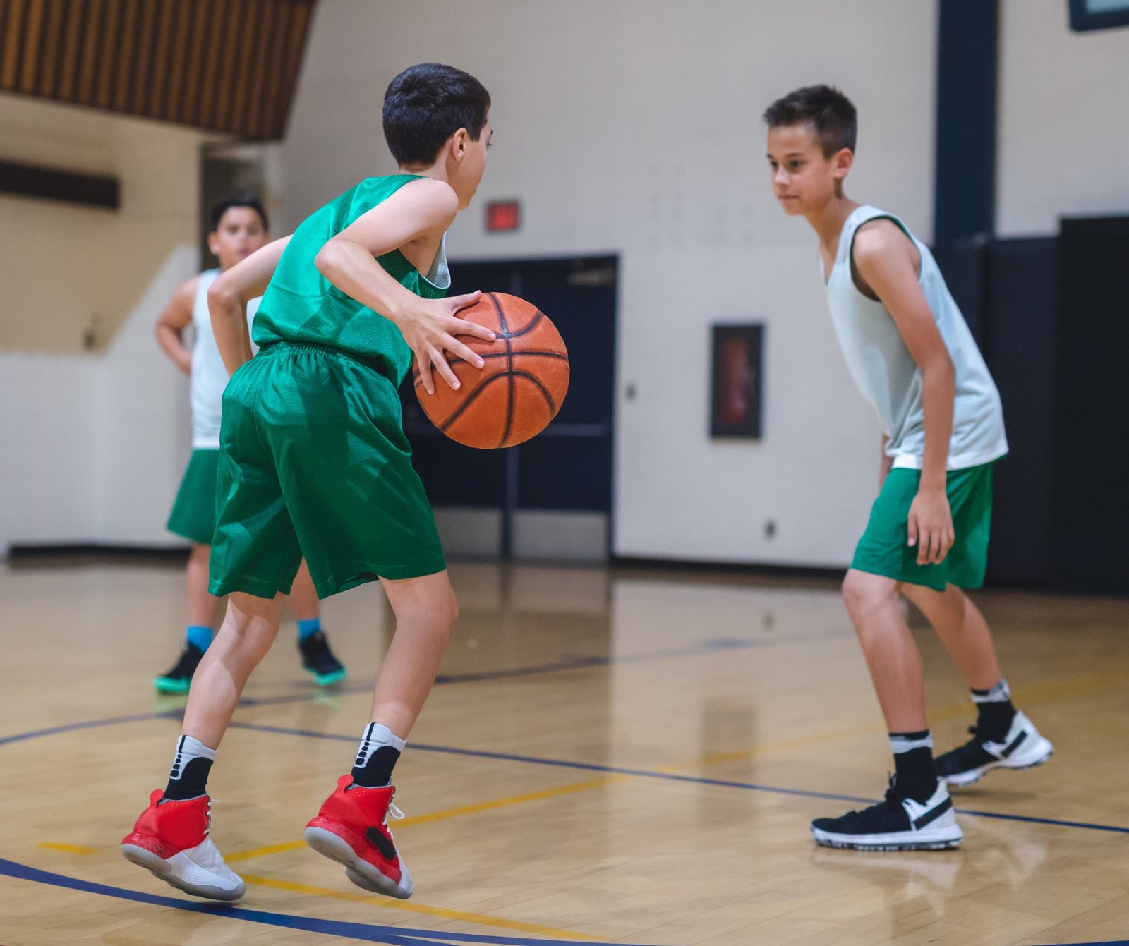 Two kids playing basketball inside a gymnasium