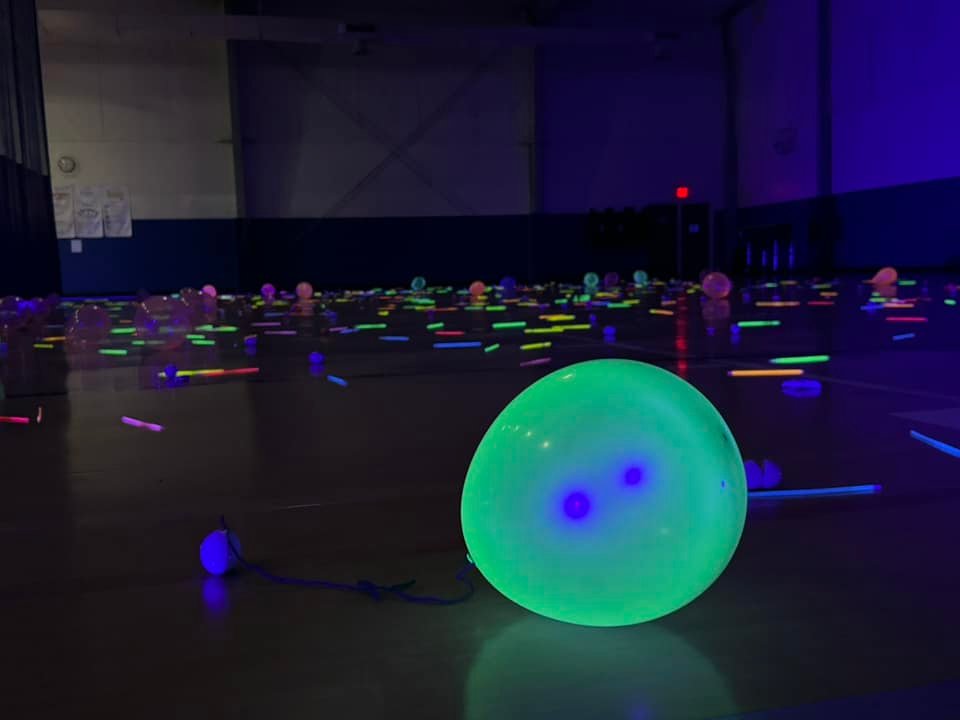 Glow in the dark balloons and glow sticks on the floor in a darkened gym for the Glow in the Dark Egg Hunt at J. Ben Harrill Recreation Center in Pasco County Florida