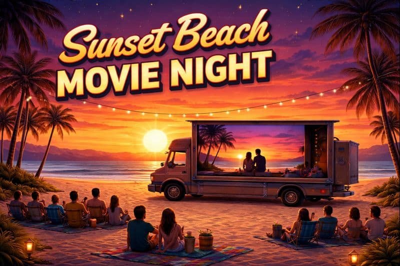 Sunset Beach movie night. A movie screen on a beach at sunset with people on blankets watching the screen.