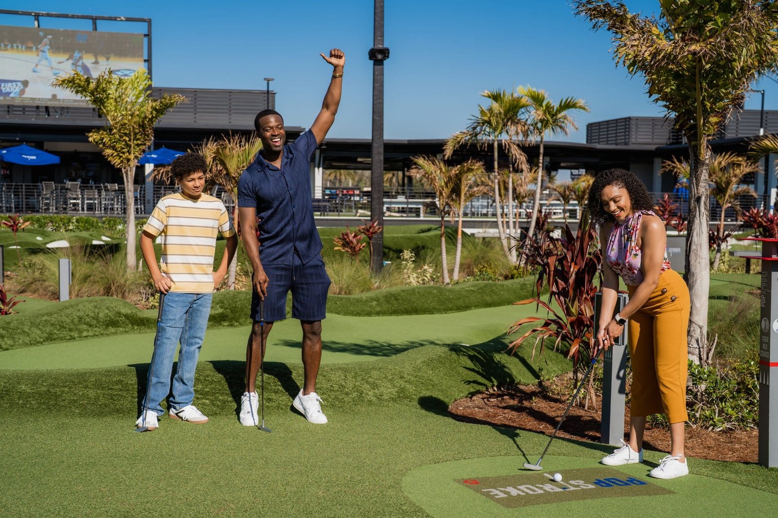 A family happily playing mini golf at PopStroke mini golf in Lutz, Florida